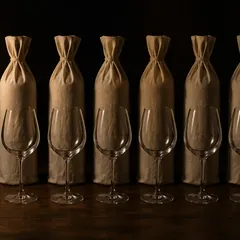 Seis botellas embolsadas para una cata a ciegas, con las copas delante
