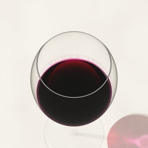 A glass of deep purple-red wine seen from above on a linen cloth