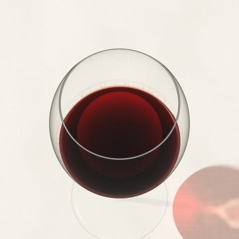 A glass of garnet red wine seen from above on a linen cloth