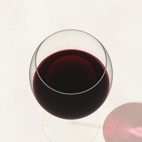 A generous pour of deep red wine seen from above on a linen cloth