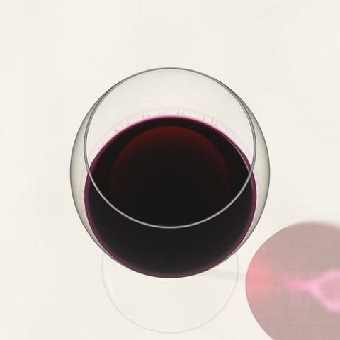Una copa de vino tinto joven, de un púrpura intenso, vista desde arriba sobre un mantel de lino