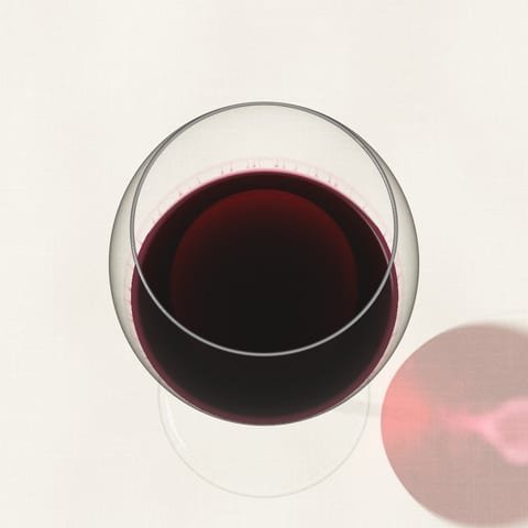 Una copa de vino tinto rubí vista desde arriba sobre un mantel de lino, atravesada por la luz